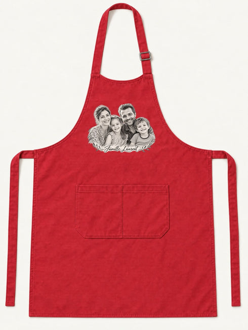 Visuel d’illustration – tablier de cuisine rouge en coton, à plat, vue de face, avec un portrait de famille fictive au crayon clair, style Croquis, texte « Famille Laurent »