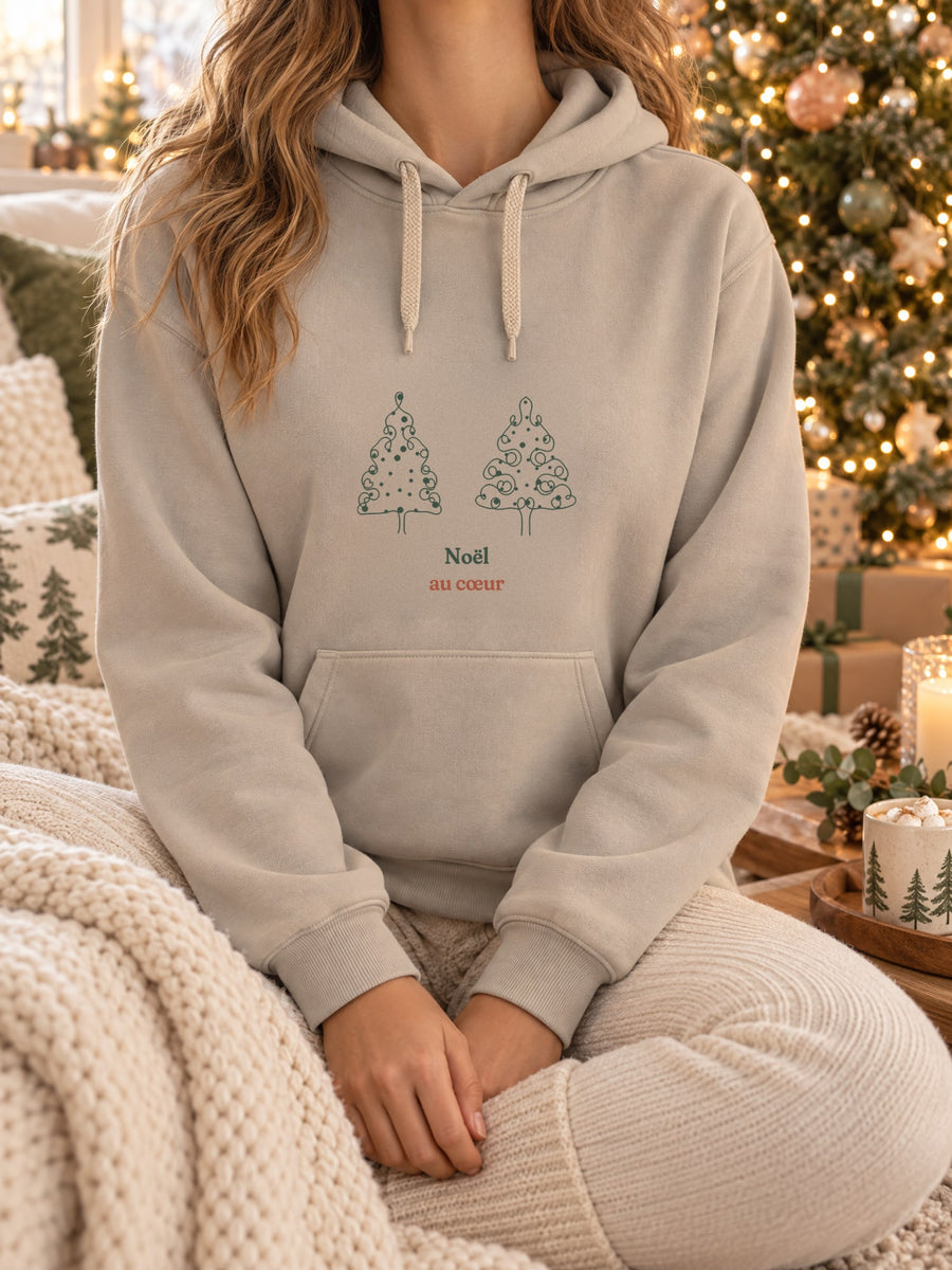 Visuel d’illustration – t-shirt dans une mise en situation, avec le motif deux sapins de Noël dessinés d’un seul trait, décorés de boules rouges et « Noël au cœur »