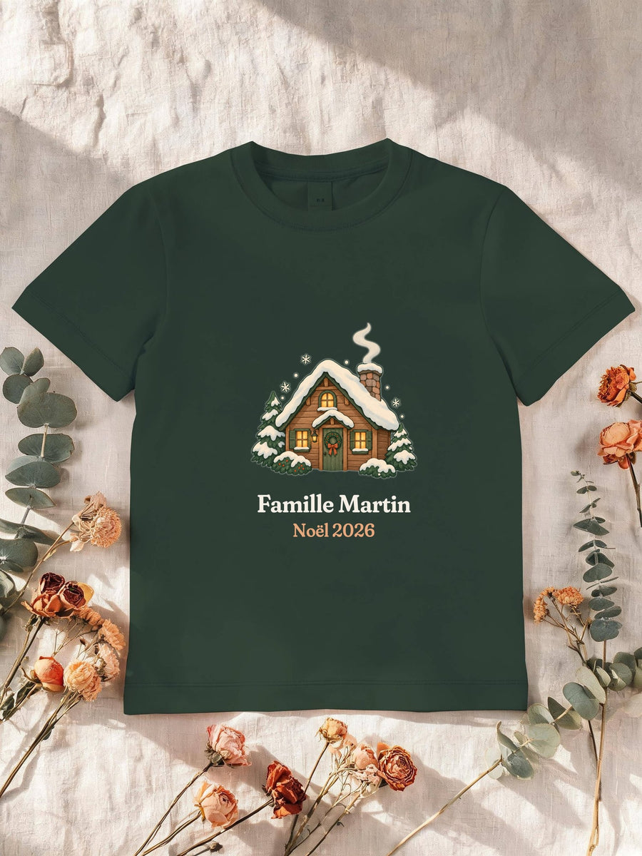 Visuel d’illustration – T-shirt enfant vert forêt avec le motif un chalet sous la neige et « Famille Martin · Noël 2026 » (exemple de nom)