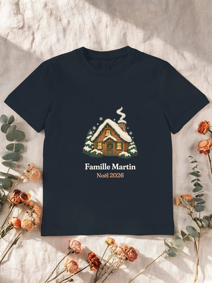 Visuel d’illustration – T-shirt enfant navy avec le motif un chalet sous la neige et « Famille Martin · Noël 2026 » (exemple de nom)