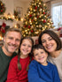 Visuel d’illustration – la photo d’origine : une famille fictive de quatre, chez elle, sapin de Noël flou derrière (personnes fictives)
