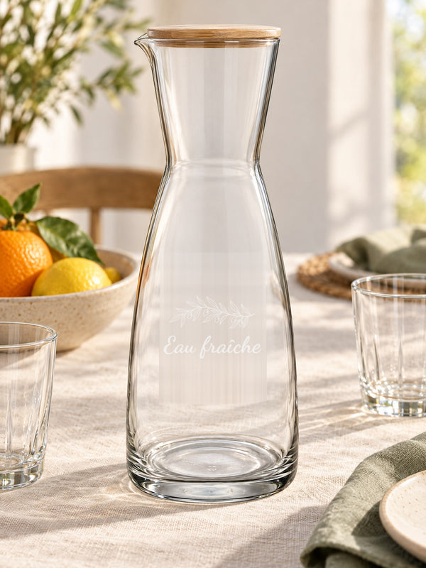 Visuel d’illustration – carafe sur une table de petit-déjeuner, gravée d’un rameau d’olivier et « Eau fraîche » (exemple)