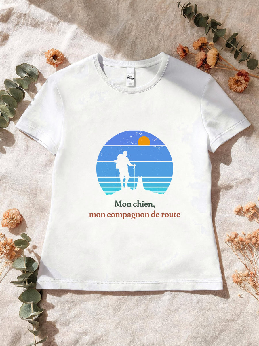 Visuel d’illustration – T-shirt femme blanc avec le motif un randonneur et son chien sur une crête, en silhouettes devant un soleil couchant à bandes rétro bleues et « Mon chien, mon compagnon de route »