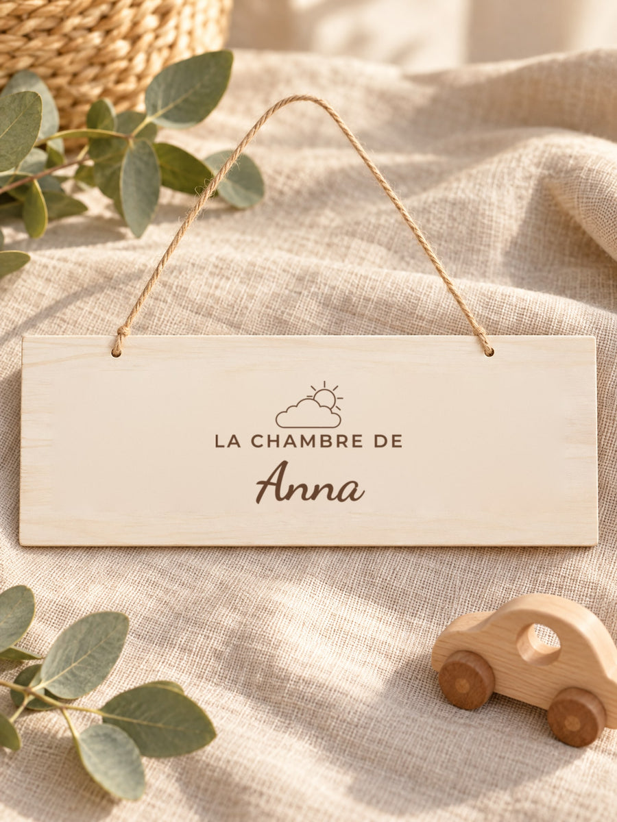 Visuel d’illustration – plaque posée sur un lin près d’une petite voiture en bois, gravée « La chambre de Anna » (exemple)