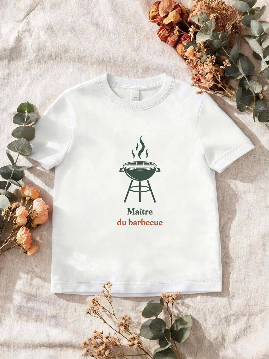 Visuel d’illustration – T-shirt homme blanc avec le motif un barbecue rond sur pieds, flammes au-dessus de la grille, en silhouette et « Maître du barbecue »