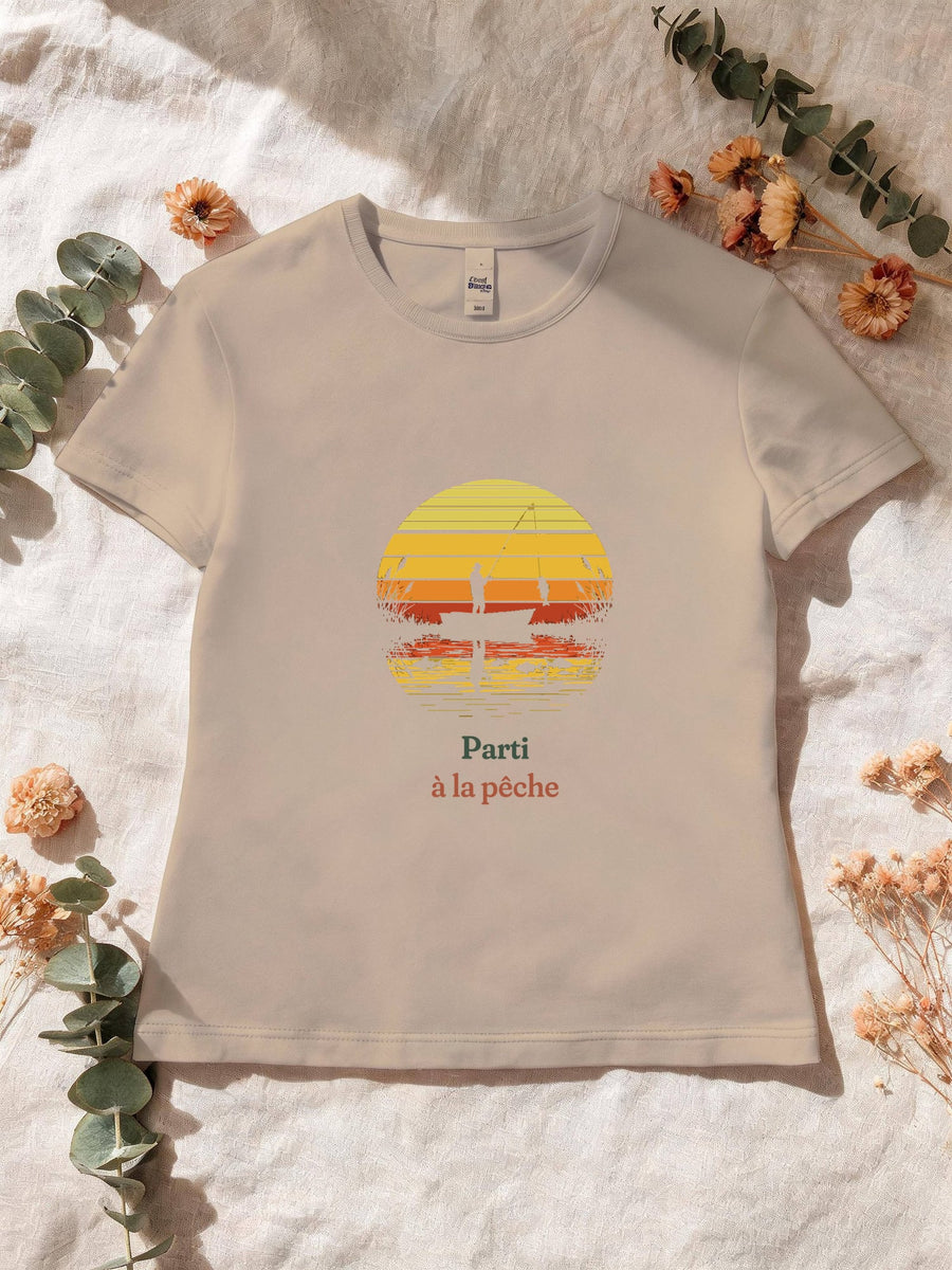 Visuel d’illustration – T-shirt femme sable avec le motif un pêcheur sur sa barque devant un soleil couchant à bandes rétro qui se reflète dans l’eau et « Parti à la pêche »