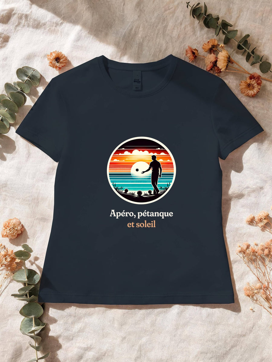 Visuel d’illustration – T-shirt femme navy avec le motif un joueur de pétanque, boules au sol, en silhouette devant un coucher de soleil sur la mer, dans un médaillon rond et « Apéro, pétanque et soleil »