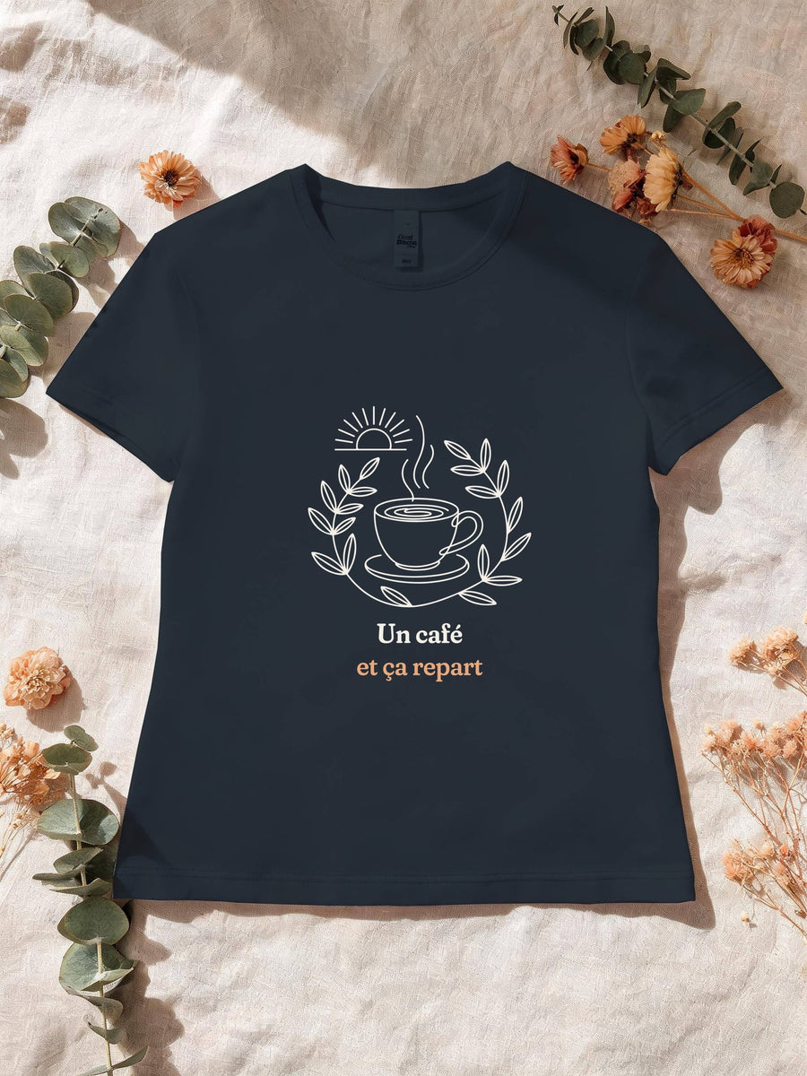 Visuel d’illustration – T-shirt femme navy avec le motif une tasse de café fumante entourée d’une couronne de feuilles, sous un soleil levant et « Un café et ça repart »