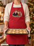 Visuel d’illustration – tablier rouge porté pour la pâtisserie de Noël, plaque de sablés et sapin illuminé, avec un portrait de couple fictif en style Portrait signature, prénoms clairs « Camille & Hugo »