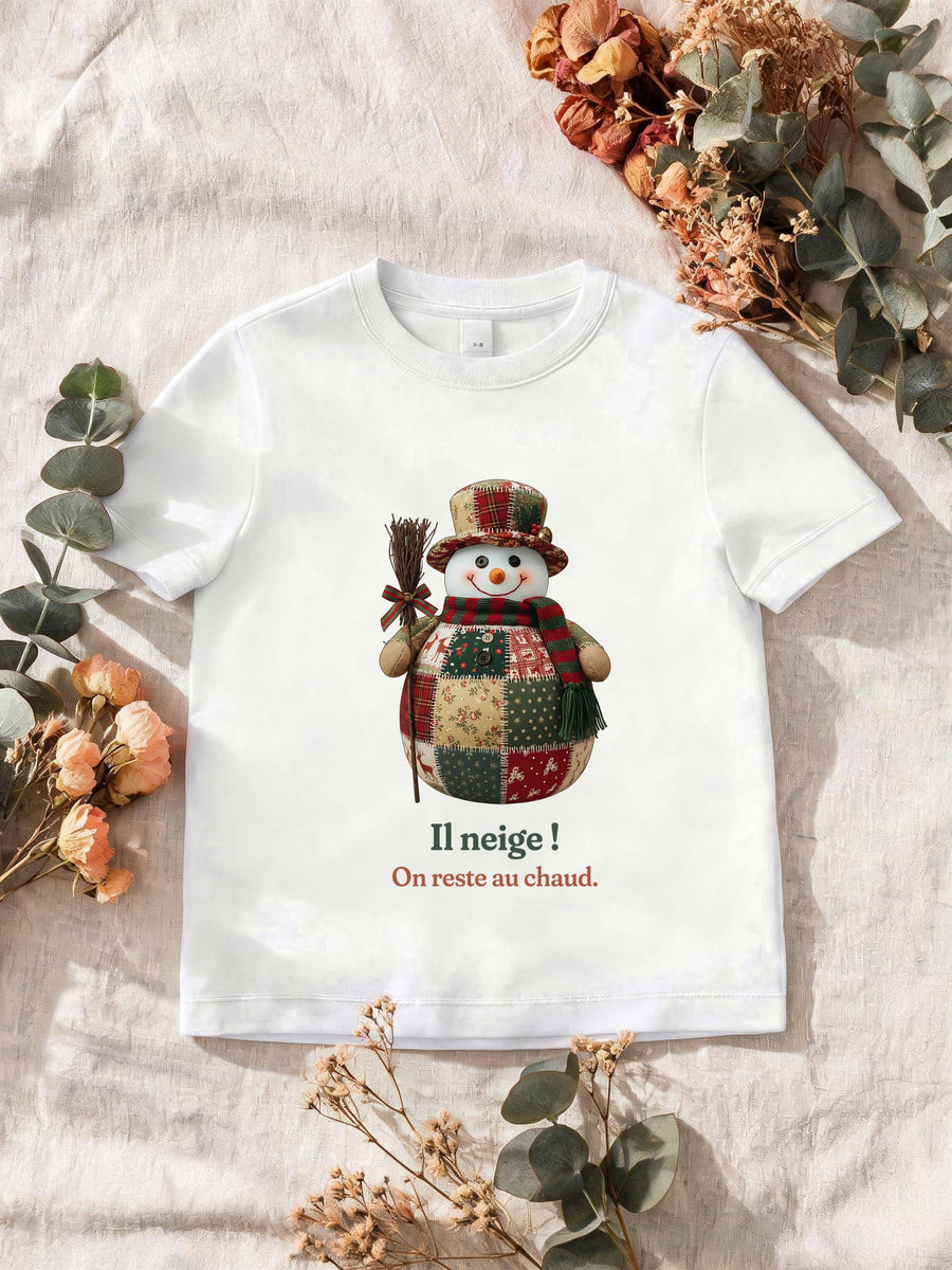 Visuel d’illustration – T-shirt homme blanc avec le motif un bonhomme de neige en patchwork et « Il neige ! » et « On reste au chaud. »