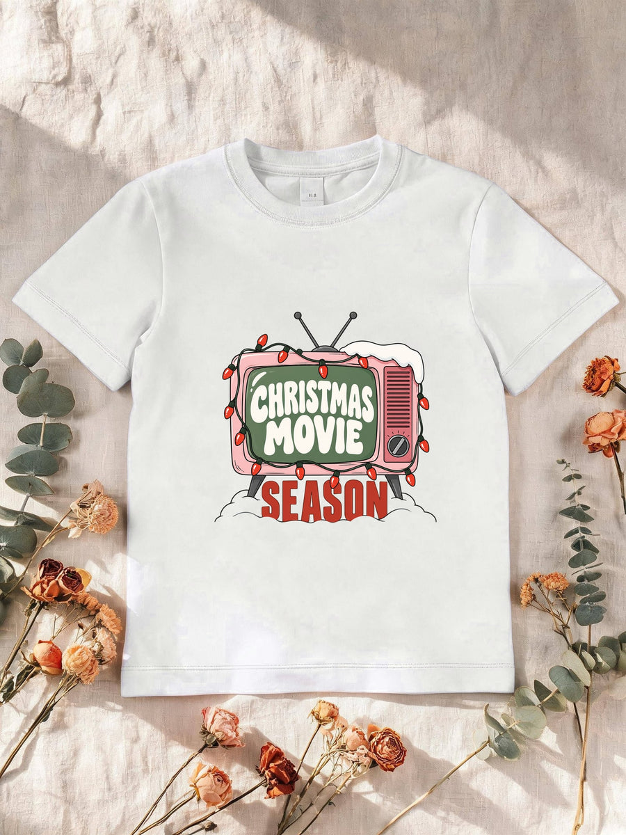Visuel d’illustration – T-shirt enfant blanc avec la télé rétro rose et sa guirlande, « Christmas Movie Season »