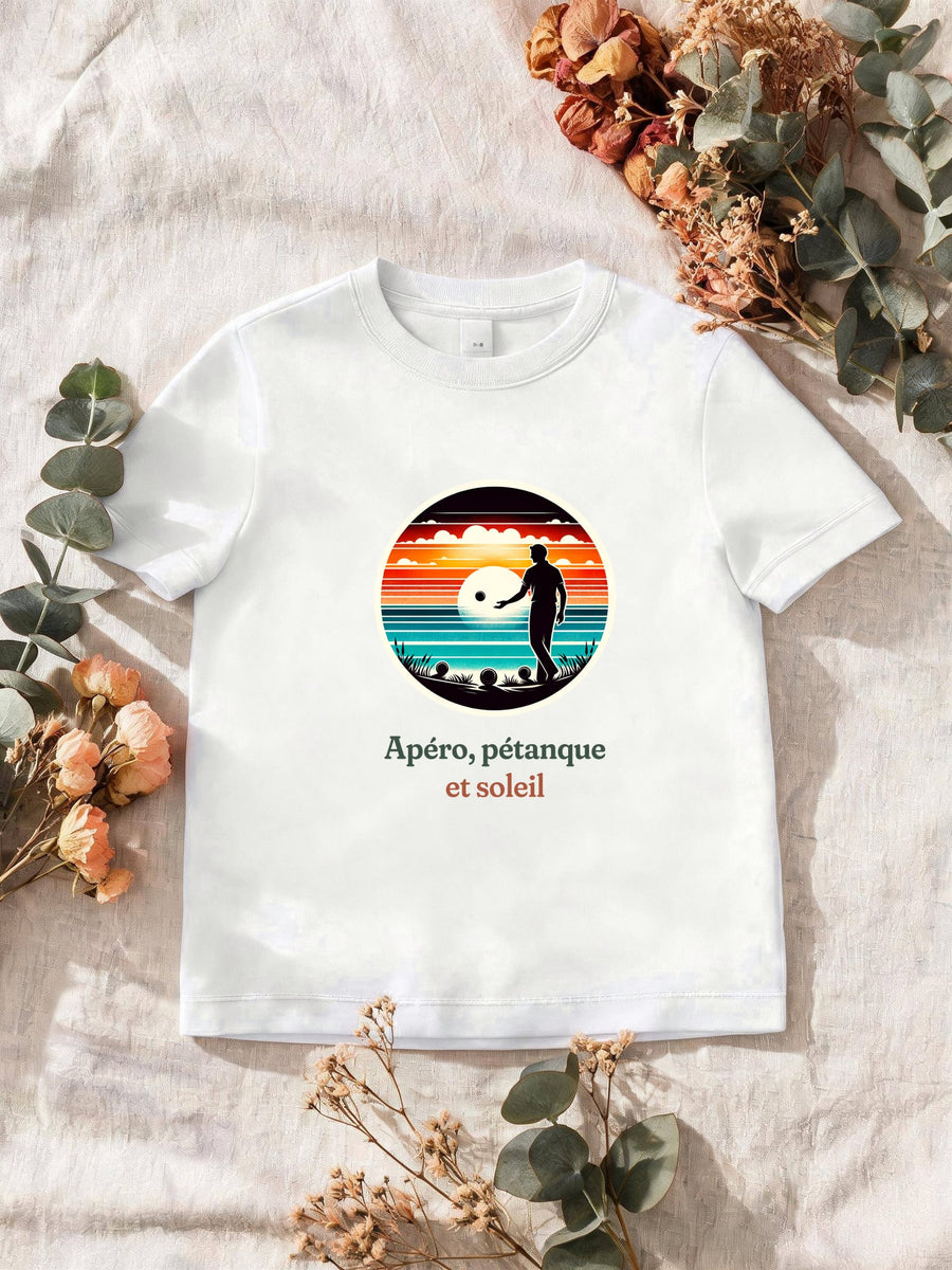 Visuel d’illustration – T-shirt homme blanc avec le motif un joueur de pétanque, boules au sol, en silhouette devant un coucher de soleil sur la mer, dans un médaillon rond et « Apéro, pétanque et soleil »