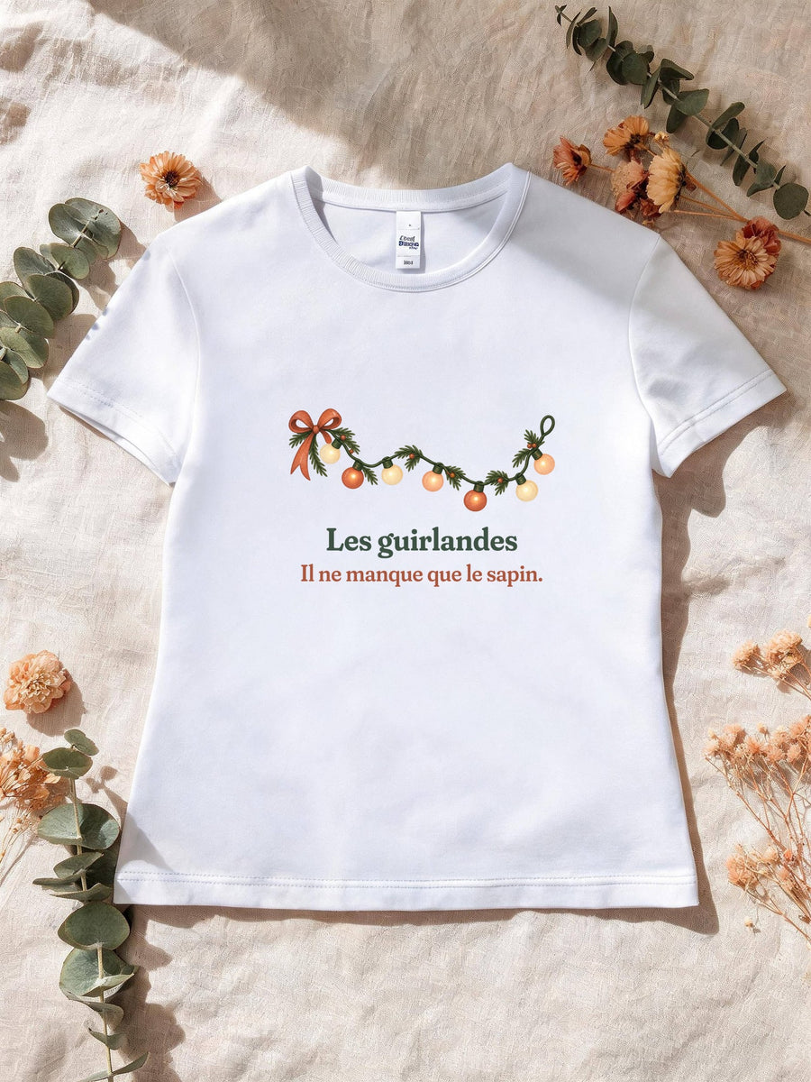 Visuel d’illustration – T-shirt femme blanc avec le motif une guirlande lumineuse et « Les guirlandes. Il ne manque que le sapin. »