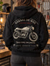 Visuel d’illustration : femme de dos dans un atelier, sweat noir avec le dessin Garage vintage d’une moto en grand dans le dos