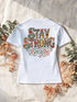 T-shirt femme blanc, lettering floral « Stay Strong Breathe » imprimé au dos, posé sur lin et eucalyptus