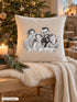 Visuel d’illustration – housse de coussin naturel au pied du sapin, avec un plaid crème et des bougies, avec un portrait de famille au crayon, style Croquis, texte « Famille Laurent »