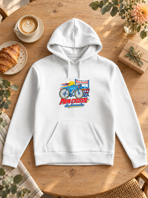 Visuel d’illustration – Sweat à capuche blanc avec le design « Papa cycliste du dimanche », posé à plat sur une table de café, avec les prénoms d’exemple