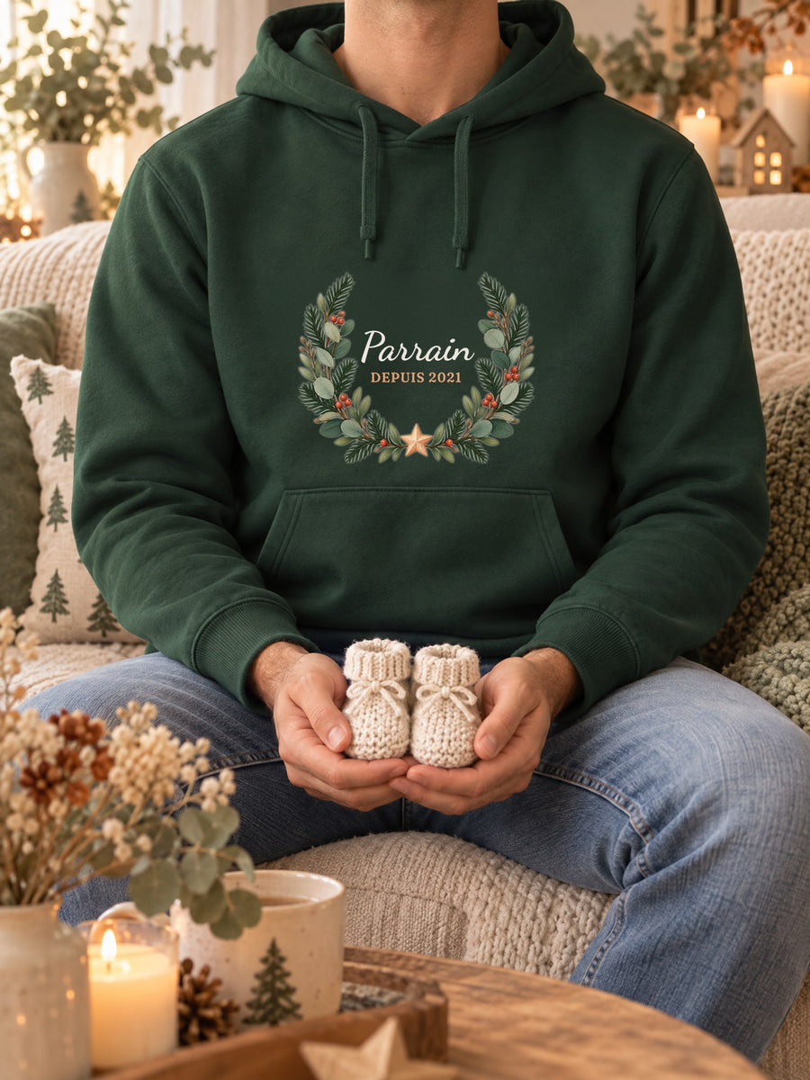 Visuel d’illustration – sweat à capuche vert forêt dans une mise en situation, avec le motif une couronne de sapin et « Parrain depuis 2021 » (exemple d’année)