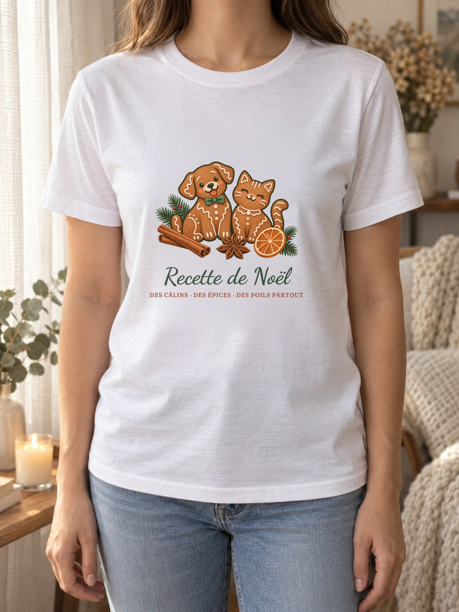 Visuel d’illustration – t-shirt blanc porté, près d’un rideau de lin et d’une bougie, avec le motif de Noël : deux biscuits de pain d’épices en forme de chien et de chat et le texte « Recette de Noël : des câlins, des épices, des poils partout »