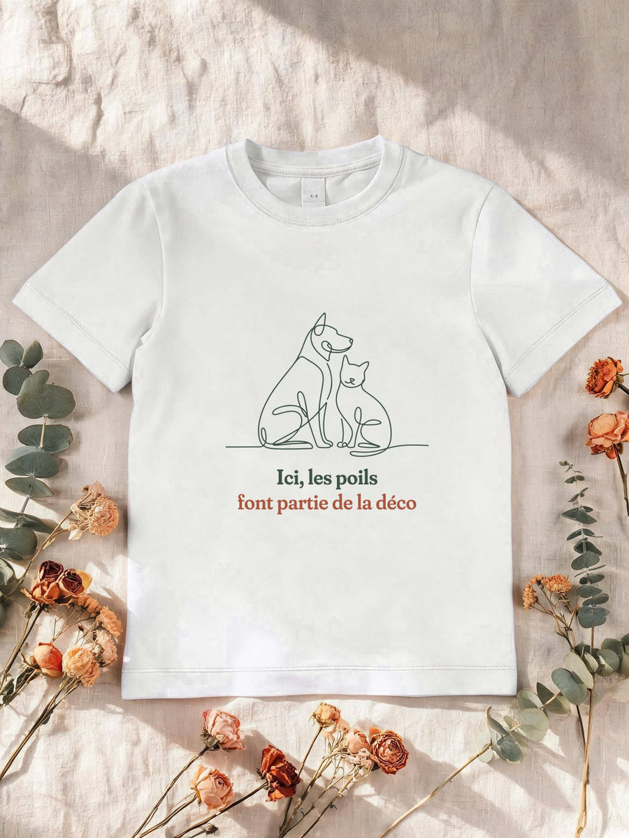 Visuel d’illustration – T-shirt enfant blanc avec le motif un chien et un chat assis côte à côte, dessinés d’un seul trait continu et « Ici, les poils font partie de la déco »