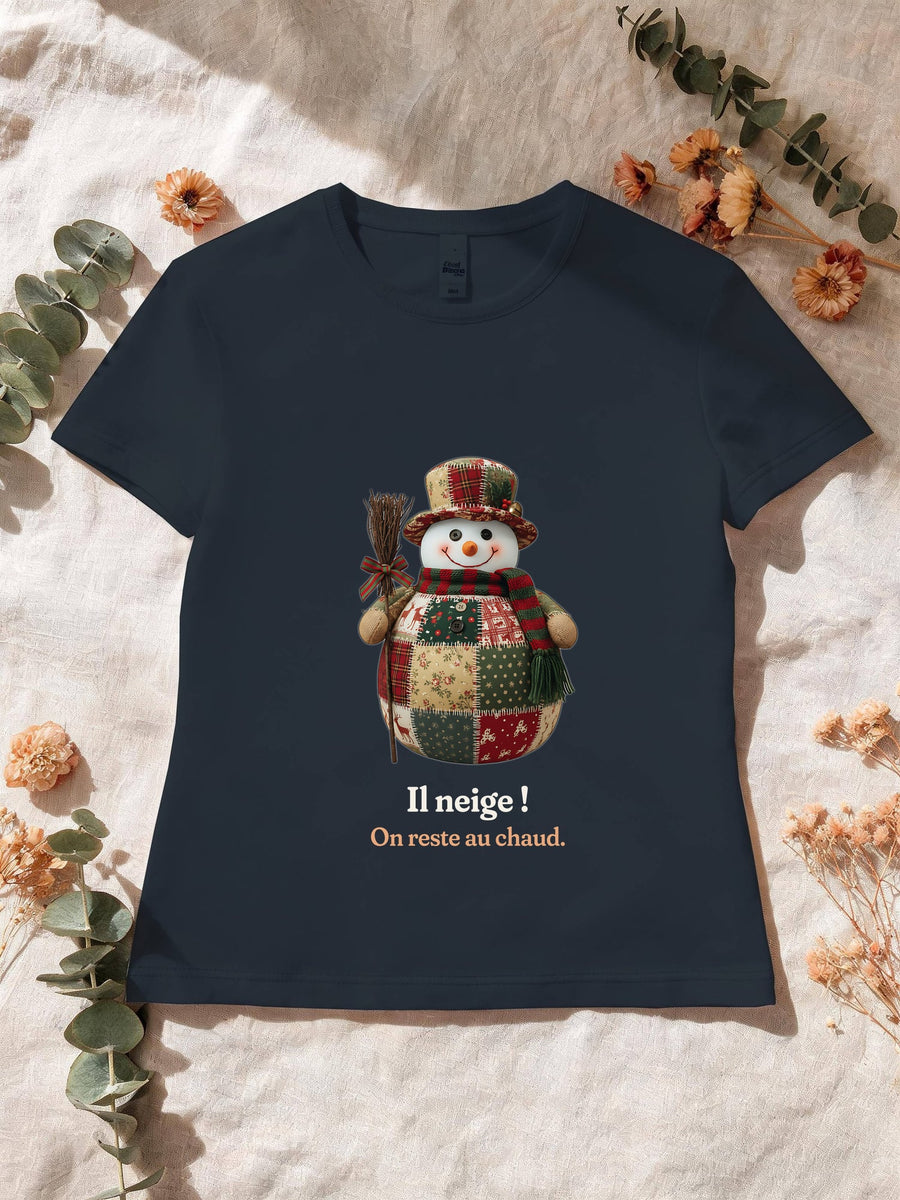 Visuel d’illustration – T-shirt femme navy avec le motif un bonhomme de neige en patchwork et « Il neige ! » et « On reste au chaud. »