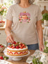 Visuel d’illustration – Grand-mère portant un t-shirt sable personnalisé « Mamie, reine des gâteaux » avec les prénoms Léa, Tom et Zoé
