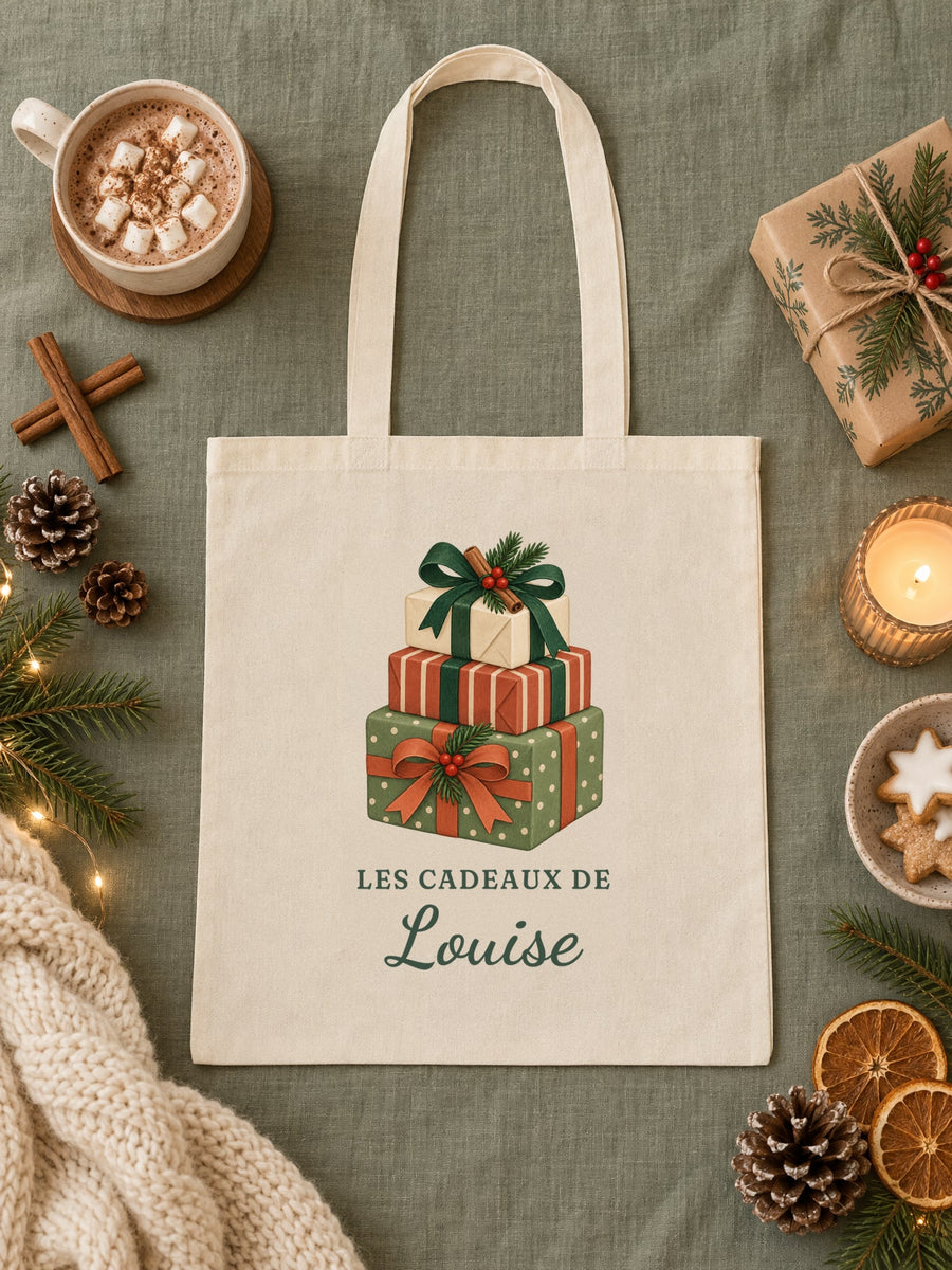 Visuel d’illustration – tote bag « Les cadeaux de Louise » posé à plat sur une nappe vert sauge, près d’un chocolat chaud