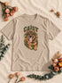 T-shirt homme Desert Dust personnalisé avec le portrait Campus détouré de Caisy, sur un décor en lin et fleurs séchées.