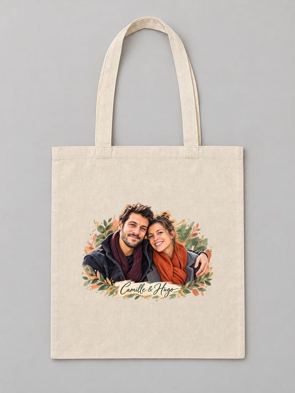 Visuel d’illustration – tote bag en coton naturel écru, à plat, vue de face, avec un portrait de couple fictif en style Portrait signature, prénoms « Camille & Hugo »