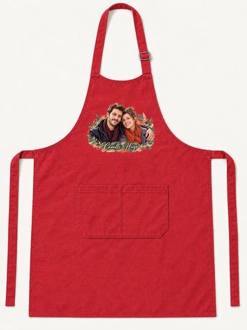 Visuel d’illustration – tablier de cuisine rouge en coton, à plat, vue de face, avec un portrait de couple fictif en style Portrait signature, prénoms clairs « Camille & Hugo »