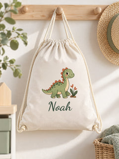 Visuel d’illustration – sac à cordon suspendu à une patère en bois dans une chambre d’enfant, imprimé d’un petit dinosaure et « Noah » (exemple)