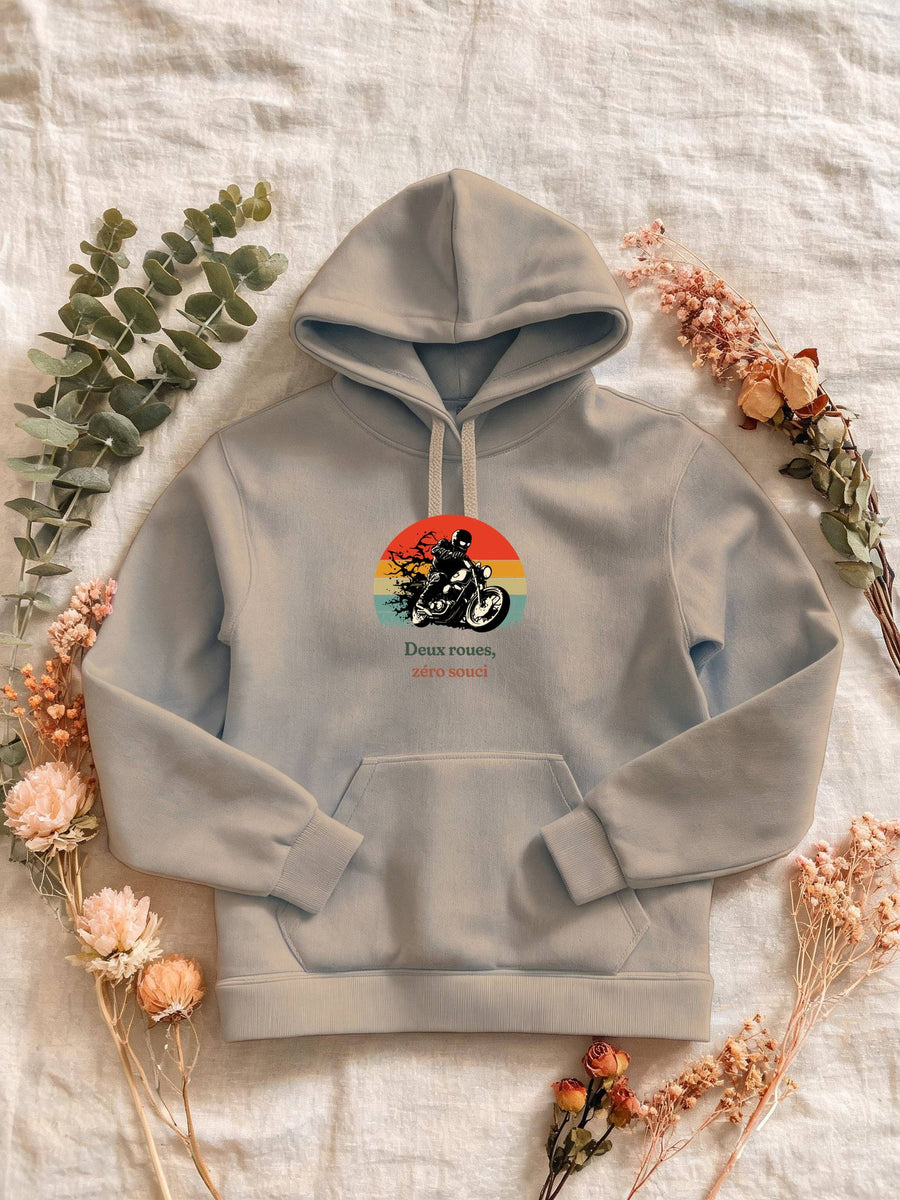 Visuel d’illustration – Sweat femme sable avec le motif un motard casqué sur sa moto, en silhouette devant un soleil couchant à bandes rétro et « Deux roues, zéro souci »