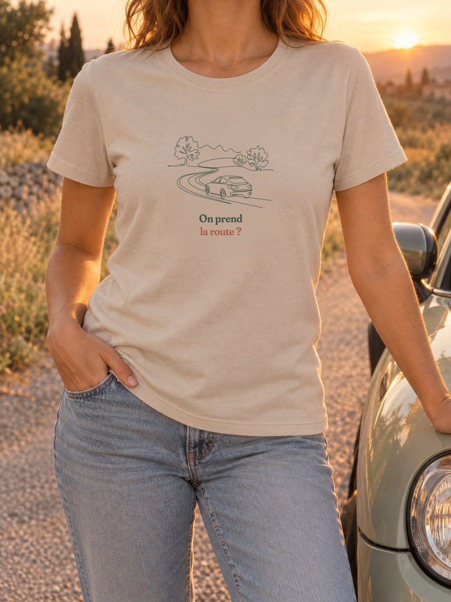 Visuel d’illustration – t-shirt dans une mise en situation, avec le motif une voiture sur une route sinueuse entre les arbres, dessinée d’un seul trait continu et « On prend la route ? »