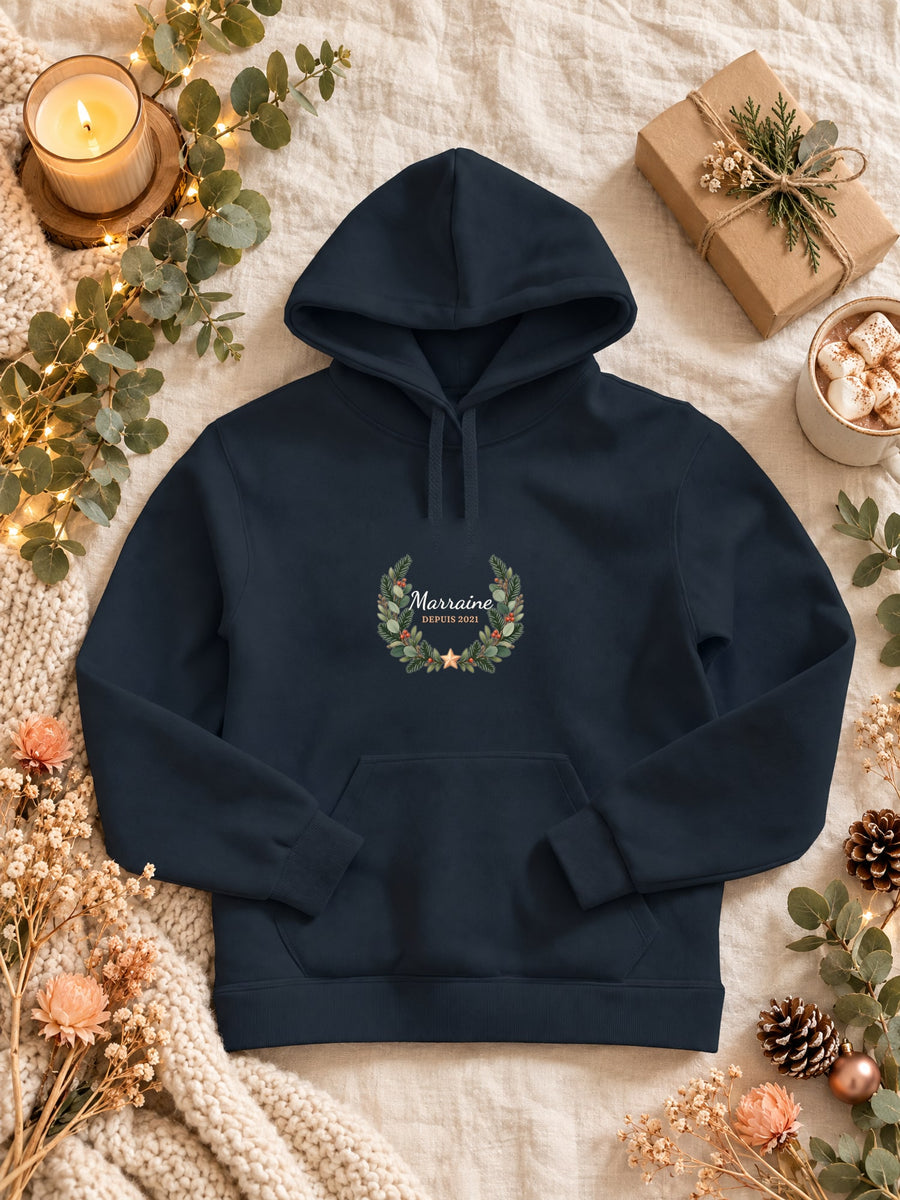 Visuel d’illustration – sweat à capuche navy dans une mise en situation, avec le motif une couronne de sapin et « Marraine depuis 2021 » (exemple d’année)