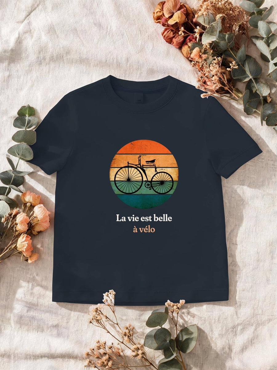 Visuel d’illustration – T-shirt homme navy avec le motif un vélo ancien à grande roue, en silhouette devant un soleil couchant à bandes rétro et « La vie est belle à vélo »