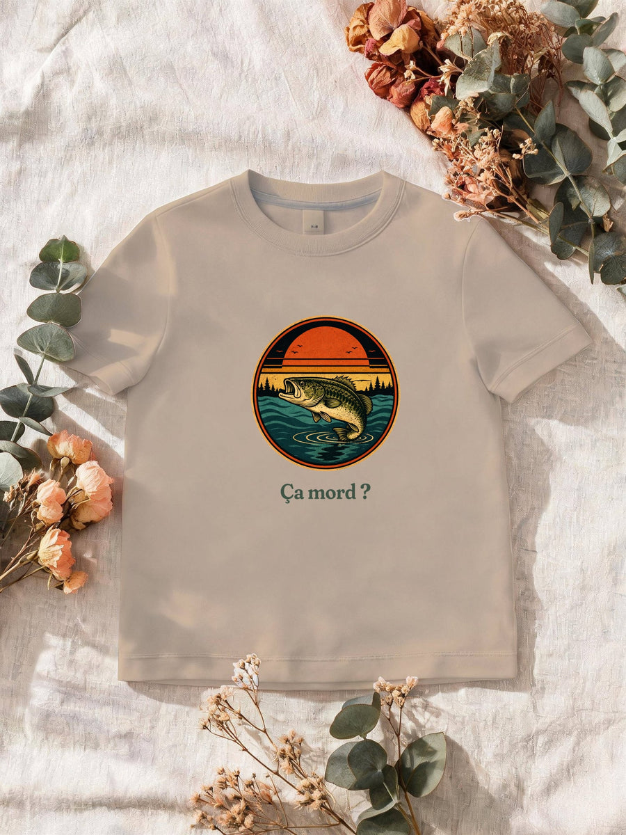 Visuel d’illustration – T-shirt homme sable avec le motif un poisson qui saute hors de l’eau devant un soleil couchant et des sapins, dans un médaillon rond et « Ça mord ? »
