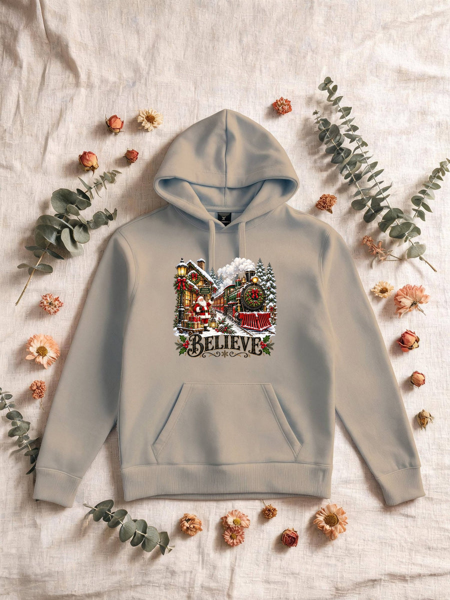 Visuel d’illustration – Sweat homme sable avec le Père Noël et le train à vapeur devant la gare enneigée, « Believe »