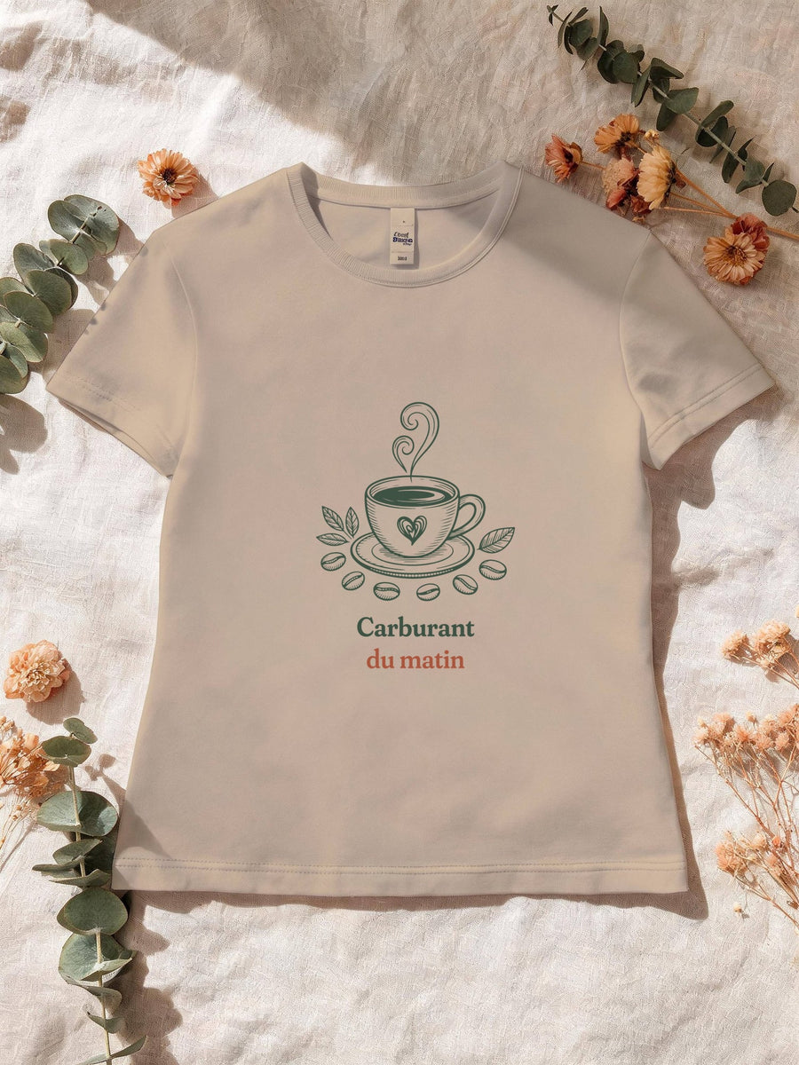Visuel d’illustration – T-shirt femme sable avec le motif une tasse de café noir à cœur, entourée de feuilles et de grains de café, d’où monte une volute et « Carburant du matin »