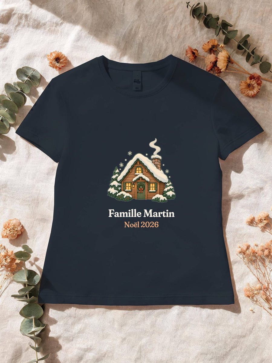 Visuel d’illustration – T-shirt femme navy avec le motif un chalet sous la neige et « Famille Martin · Noël 2026 » (exemple de nom)