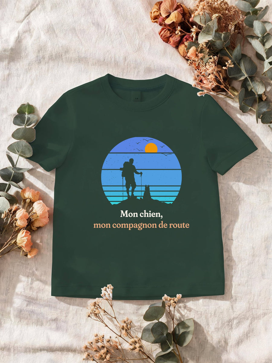 Visuel d’illustration – T-shirt homme vert forêt avec le motif un randonneur et son chien sur une crête, en silhouettes devant un soleil couchant à bandes rétro bleues et « Mon chien, mon compagnon de route »