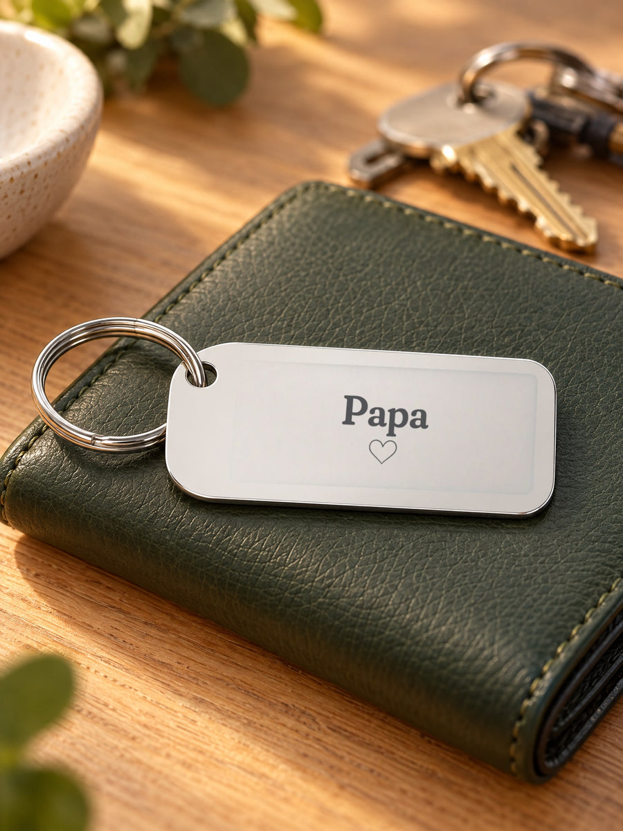 Visuel d’illustration – porte-clés en acier sur un portefeuille en cuir vert, gravé « Papa » et un petit cœur (exemple)