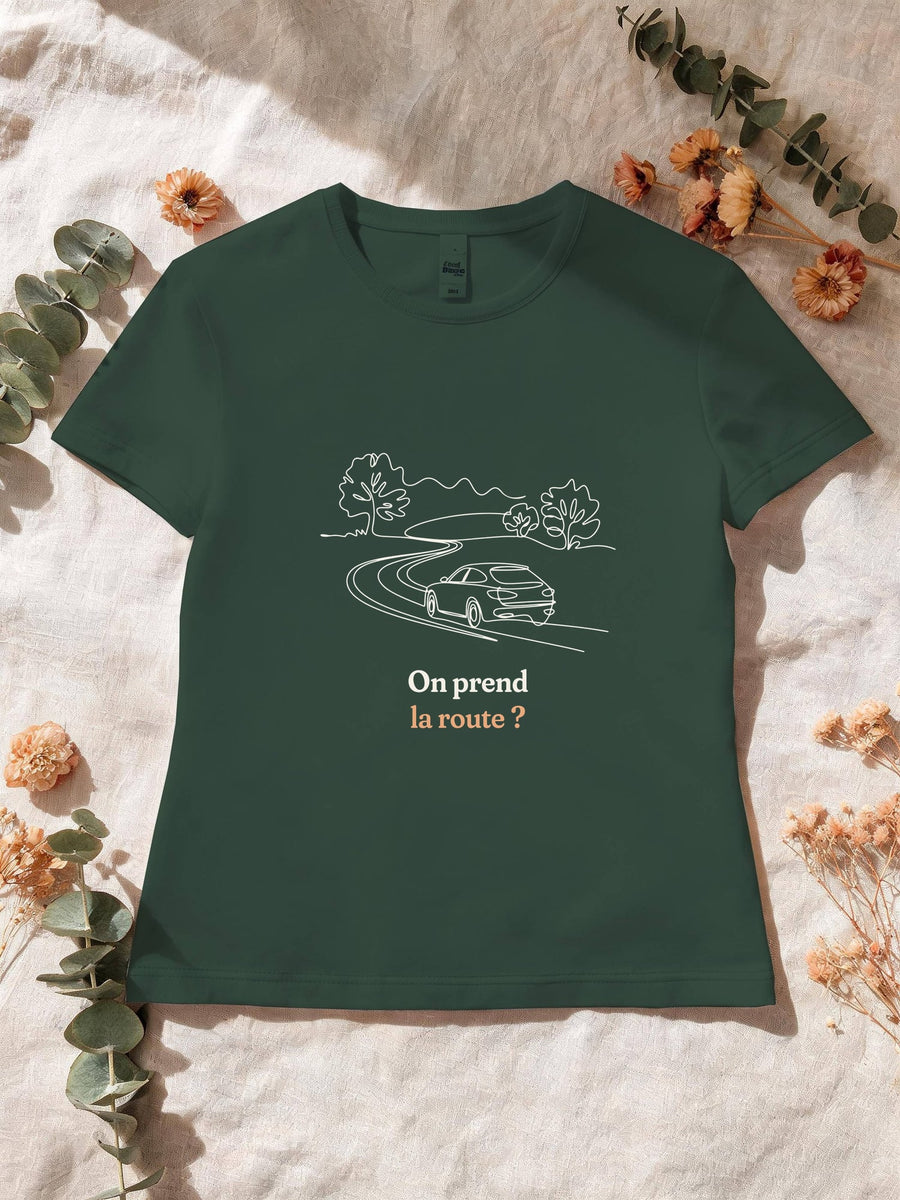 Visuel d’illustration – T-shirt femme vert forêt avec le motif une voiture sur une route sinueuse entre les arbres, dessinée d’un seul trait continu et « On prend la route ? »