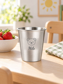 Visuel d’illustration – gobelet inox sur une table d’enfant près d’un bol de fraises, gravé d’un ourson et « Milo » (exemple)