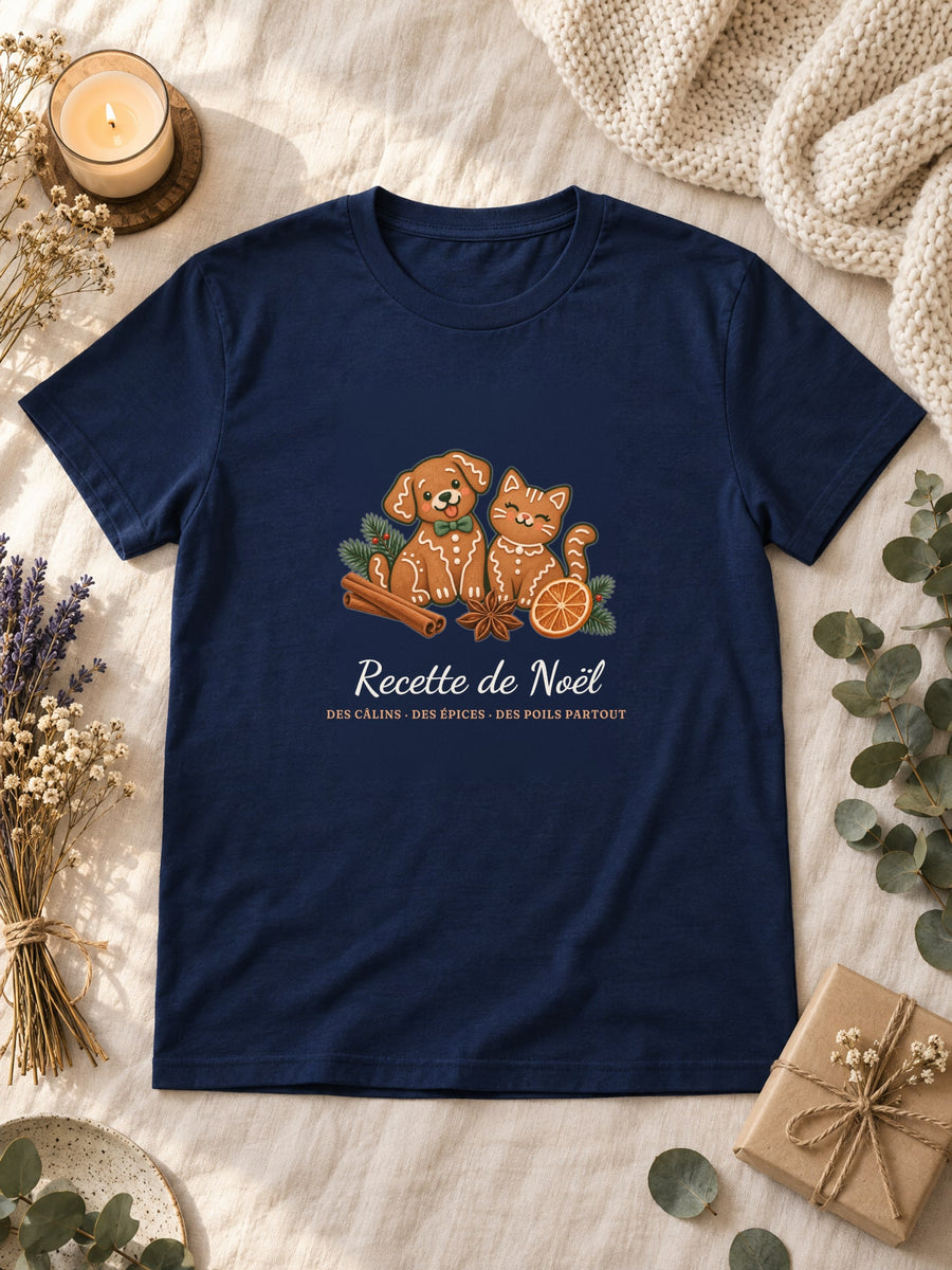 Visuel d’illustration – t-shirt navy posé à plat sur du lin, avec des fleurs séchées, une bougie et un paquet cadeau, avec le motif de Noël : deux biscuits de pain d’épices en forme de chien et de chat et le texte « Recette de Noël : des câlins, des épices, des poils partout »