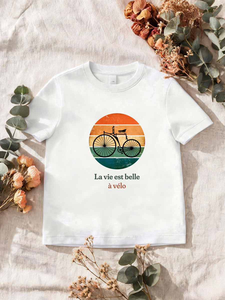 Visuel d’illustration – T-shirt homme blanc avec le motif un vélo ancien à grande roue, en silhouette devant un soleil couchant à bandes rétro et « La vie est belle à vélo »