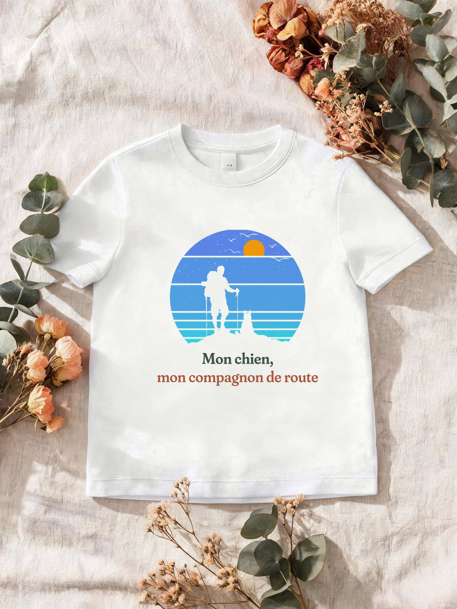 Visuel d’illustration – T-shirt homme blanc avec le motif un randonneur et son chien sur une crête, en silhouettes devant un soleil couchant à bandes rétro bleues et « Mon chien, mon compagnon de route »