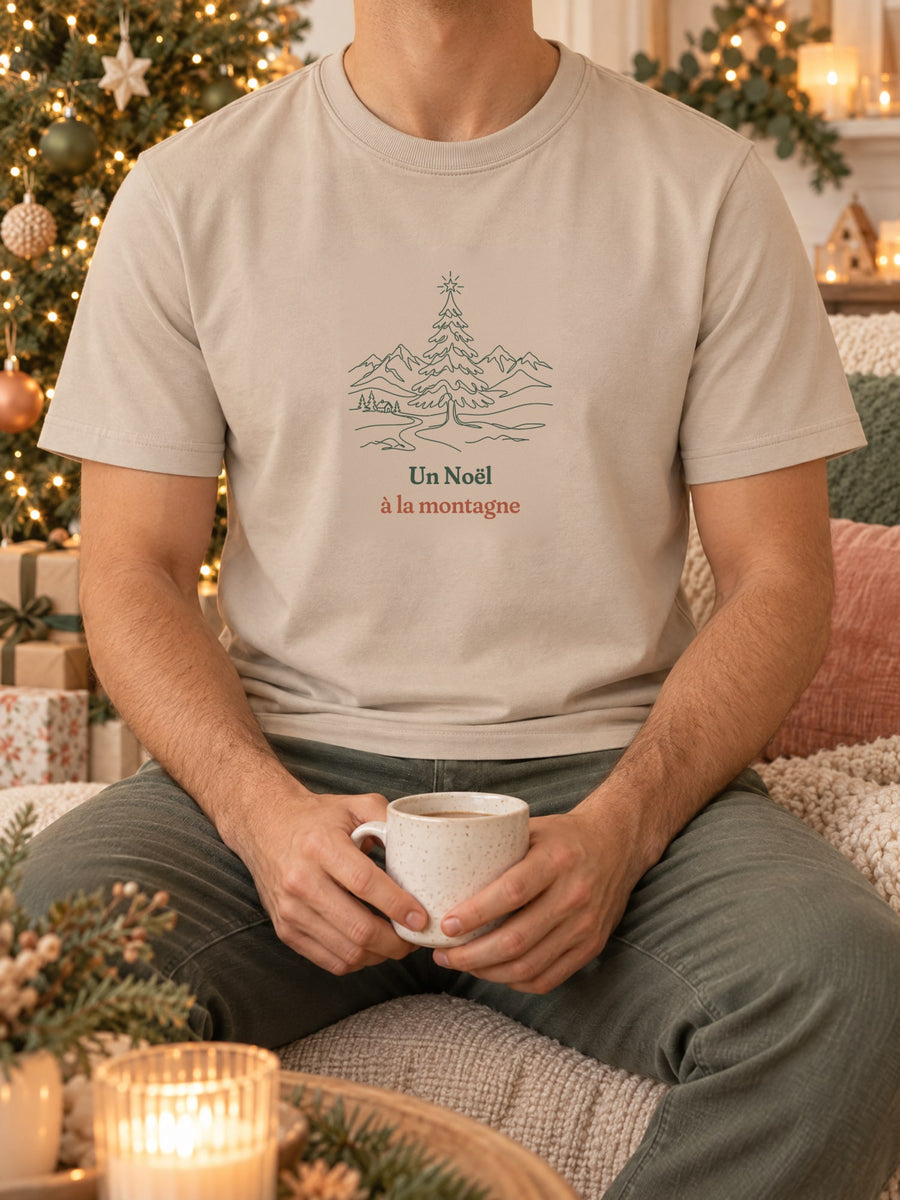 Visuel d’illustration – t-shirt dans une mise en situation, avec le motif un sapin de Noël étoilé devant des montagnes enneigées, dessiné au trait et « Un Noël à la montagne »