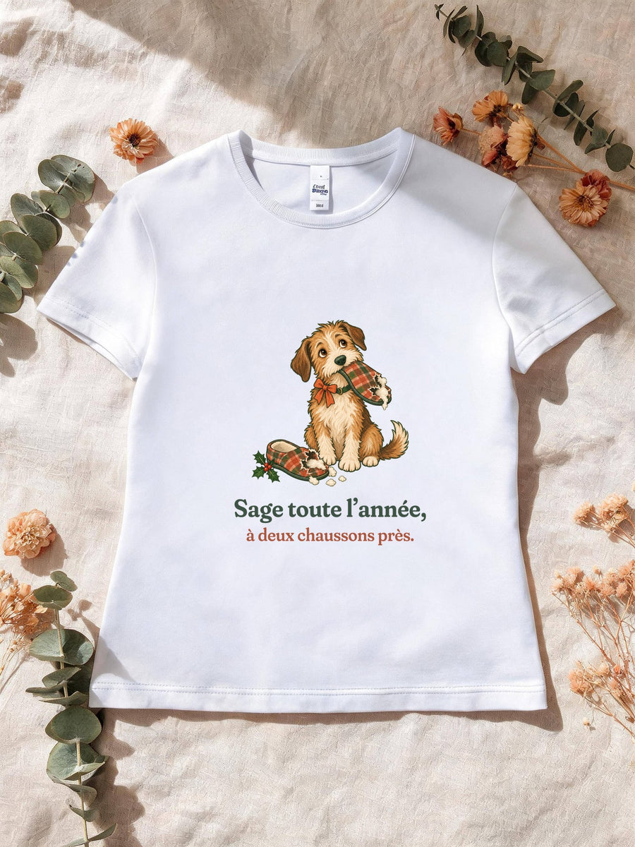 Visuel d’illustration – T-shirt femme blanc avec le motif de Noël : un chien assis, un chausson dans la gueule, et la phrase « Sage toute l’année, à deux chaussons près. »