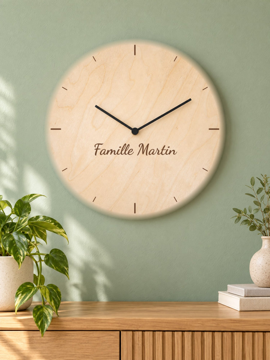 Visuel d’illustration – horloge en bois accrochée à un mur vert sauge au-dessus d’un buffet, gravée d’index et « Famille Martin » (exemple)