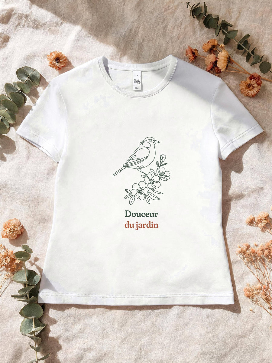 Visuel d’illustration – T-shirt femme blanc avec le motif un oiseau posé sur une branche fleurie, dessiné d’un seul trait continu et « Douceur du jardin »